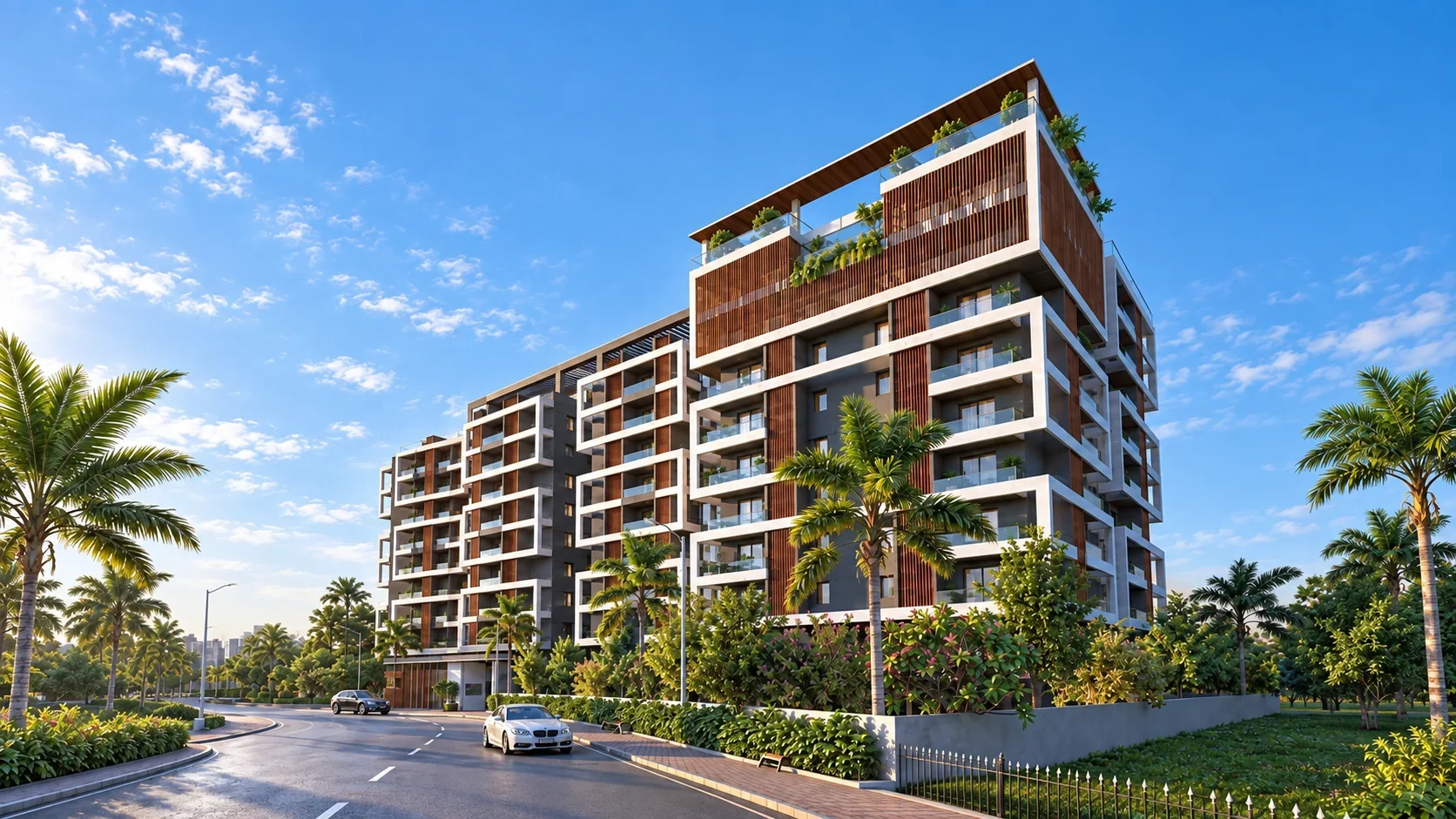 Woods Ville seen from Khamardih–Kachna Road on a clear morning: a nine-storey apartment building with white balcony frames, cedar-clad screens and a planted rooftop, set among palms.